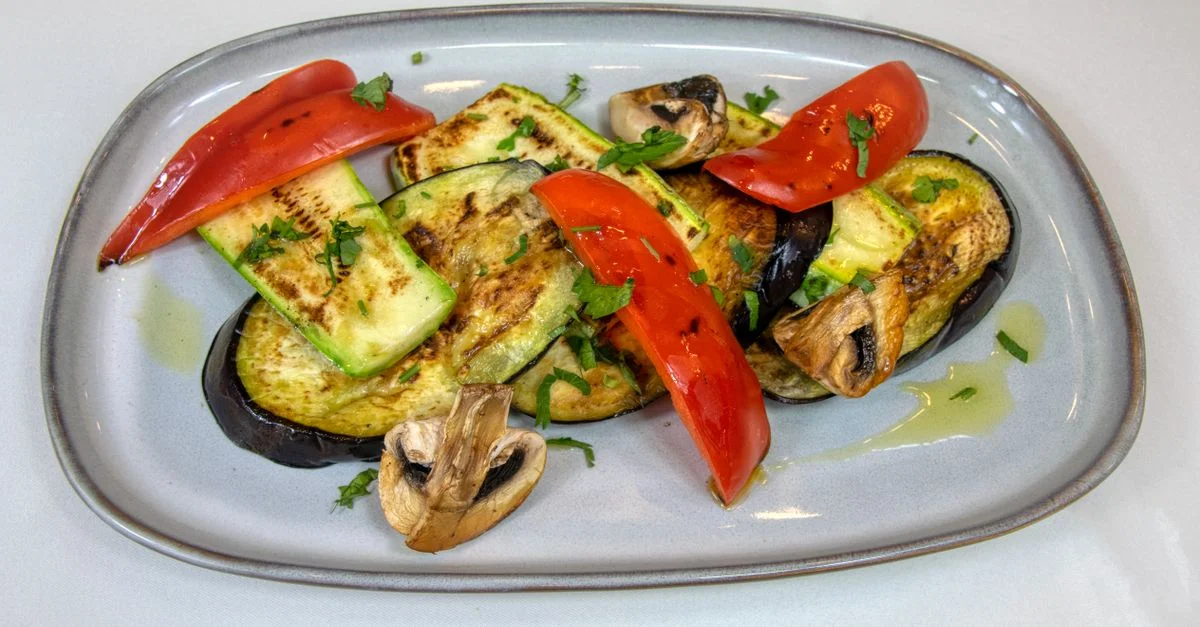 Délicieuse grillade de légumes avec aubergine, courgette et poivrons rouges sur une assiette.