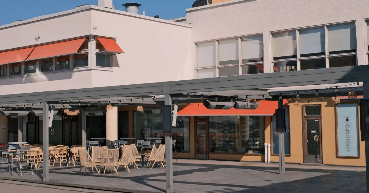 Journée ensoleillée à la terrasse d'un café à l'architecture moderne et aux places assises vides.