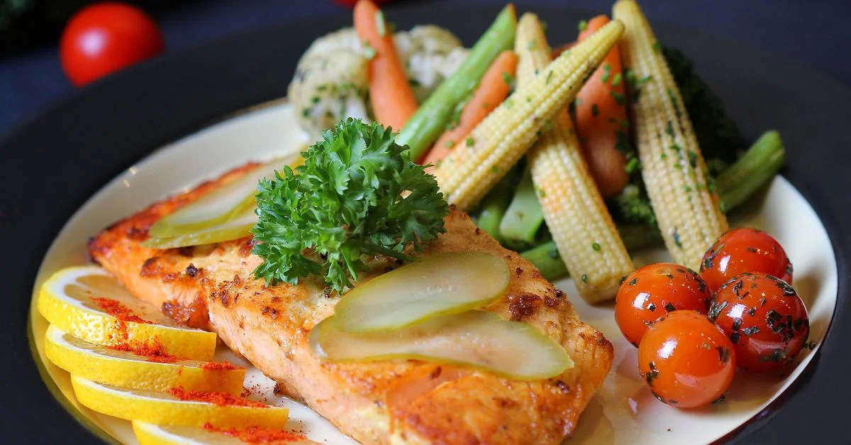 Un plat de saumon joliment dressé avec des légumes frais et des tranches de citron, parfait pour un repas gourmet.