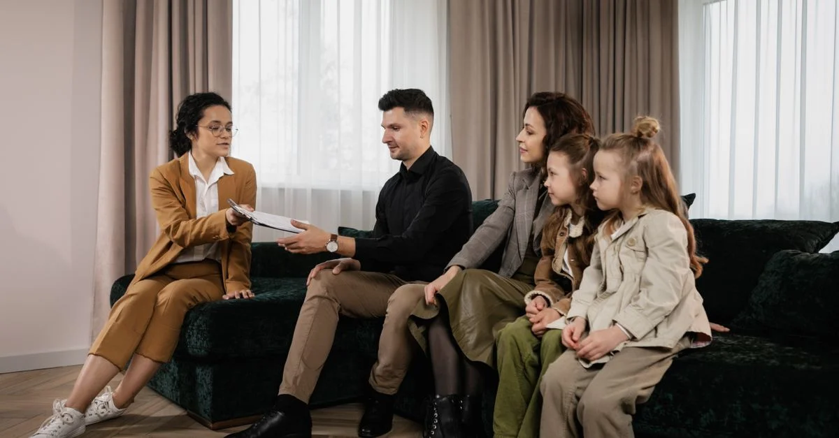 Une famille rencontre un agent immobilier dans un salon élégant, examinant des documents pour un achat de maison potentiel.