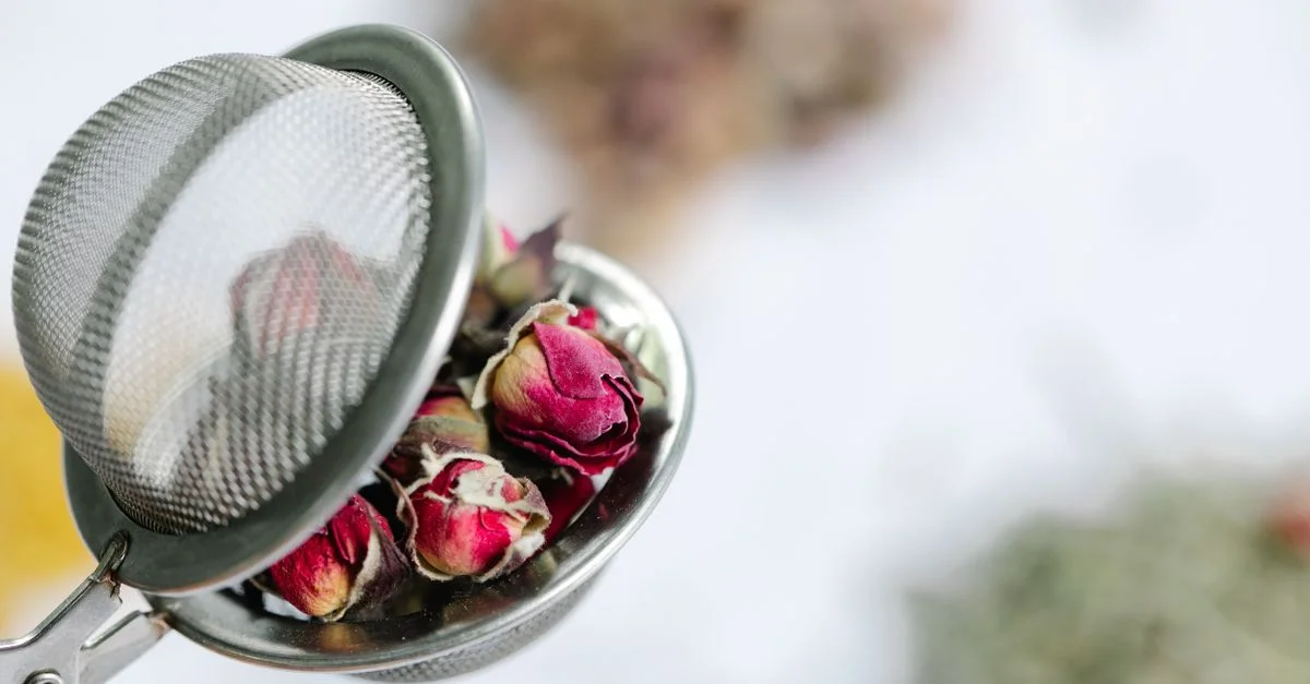 Fins boutons de rose séchés dans un infuseur à thé en maille, parfaits pour les tisanes.