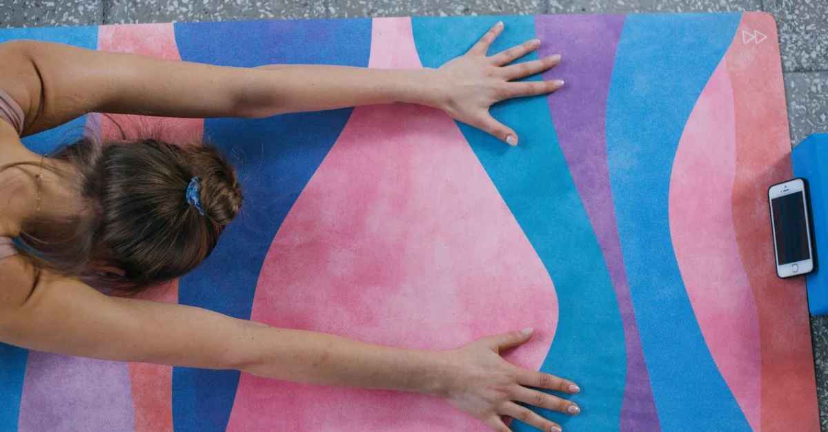 Une femme pratiquant le yoga avec un tapis coloré et un smartphone à proximité, favorisant le bien-être.