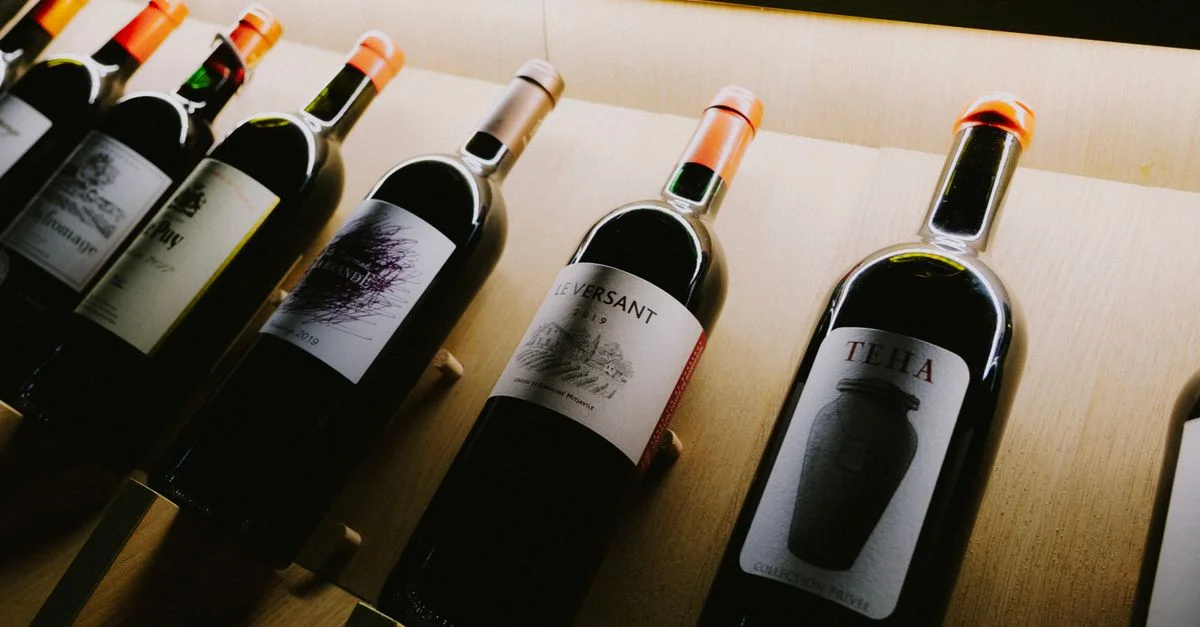 Vue rapprochée de bouteilles de vin variées sur une étagère d'exposition en bois élégante.
