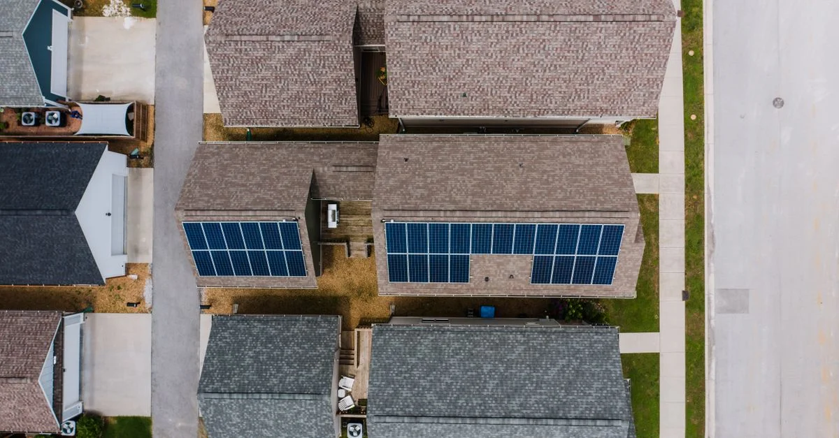 Vue de haut de maisons suburbaines avec des panneaux solaires sur les toits, mettant en valeur l'utilisation des énergies renouvelables.