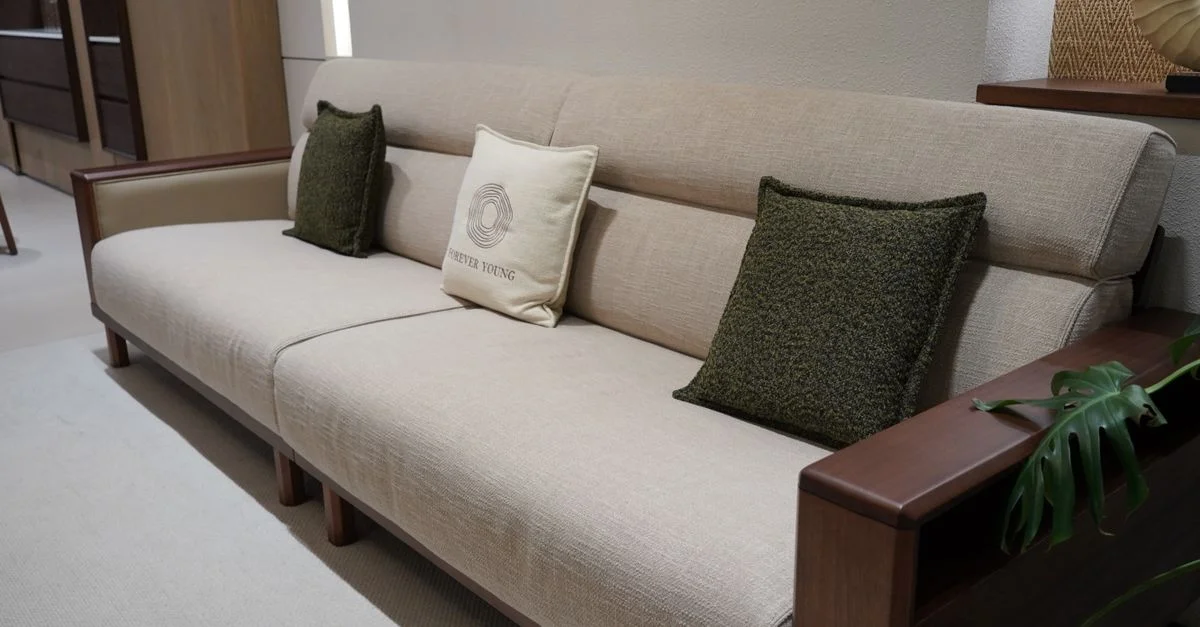 Canapé moderne et élégant avec revêtement beige et structure en bois, agrémenté de coussins verts.
