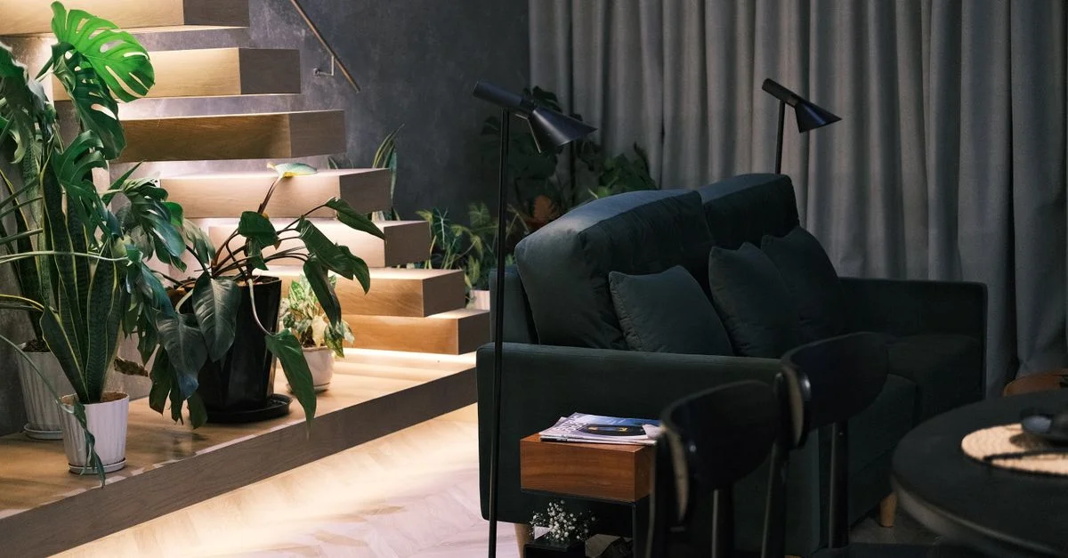 Salon élégant avec de la verdure, des escaliers et un éclairage doux. Décor moderne et cosy.