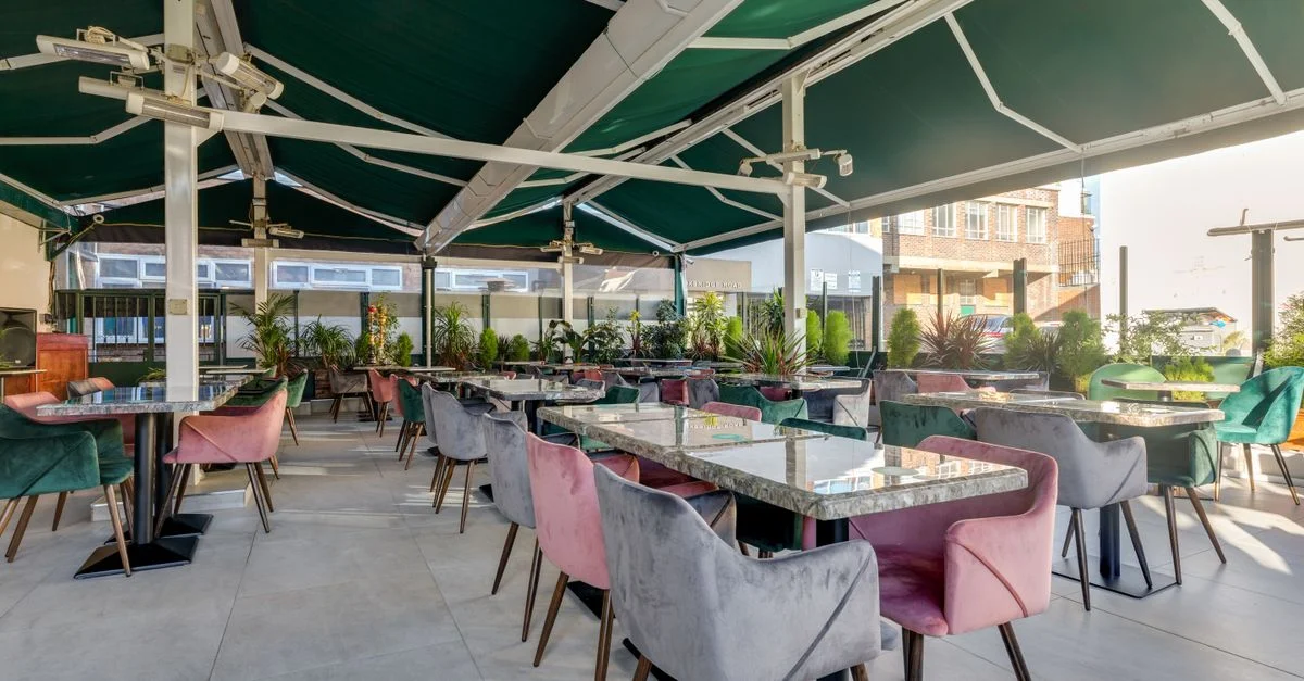 Un café spacieux en terrasse avec des fauteuils vibrants et des plantes luxuriantes.